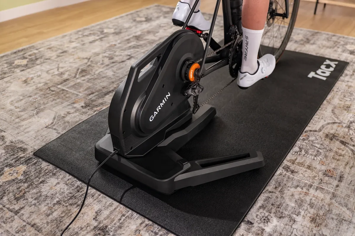 Tacx Nēra Tacx Nēra – detail trenažéru s řetězem a rozloženými nohami na podložce