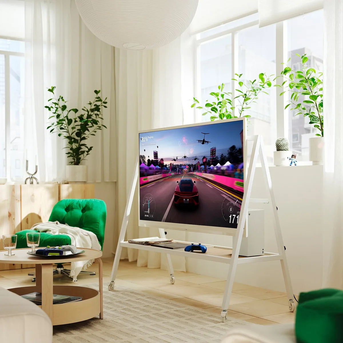 IKEA YXSTABY herní TV stolek s kolečky IKEA YXSTABY herní TV stolek s kolečky – bílý stojan s televizí, konzolí Xbox a ovladačem v obývacím pokoji