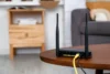 Černý Wi-Fi router se dvěma anténami na kulatém stolku v obývacím pokoji