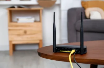 Černý Wi-Fi router se dvěma anténami na kulatém stolku v obývacím pokoji