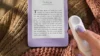 Kindle Click: bílý ovladač v ruce vedle fialové čtečky Kindle na pletené dece