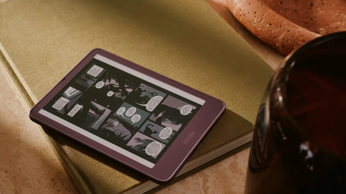 Nové Kindly 2026 mají displej zarovnaný s rámečkem a základní model váží jen 140 gramů 19 Kindle Colorsoft Signature Edition – barevná čtečka v odstínu Fig s komiksem na displeji, položená na stole