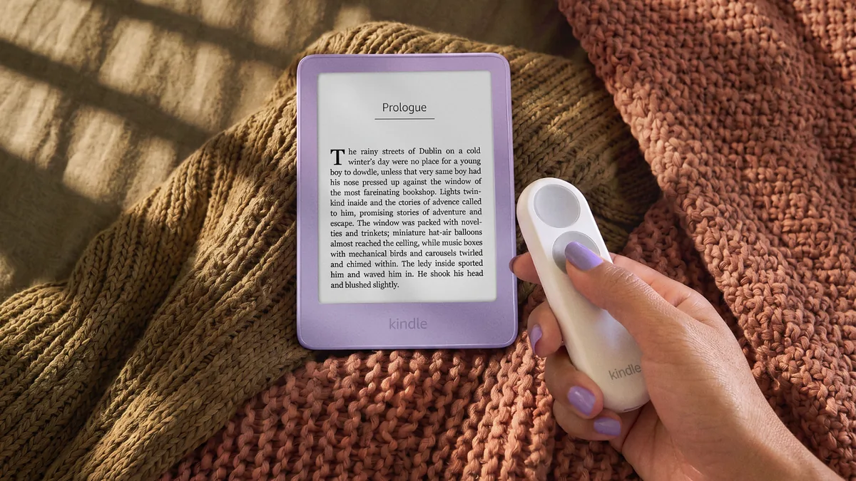 Nové Kindly 2026 mají displej zarovnaný s rámečkem a základní model váží jen 140 gramů 21 Kindle Click – bluetoothové ovládání v ruce vedle Kindlu v barvě Ube na pletené dece